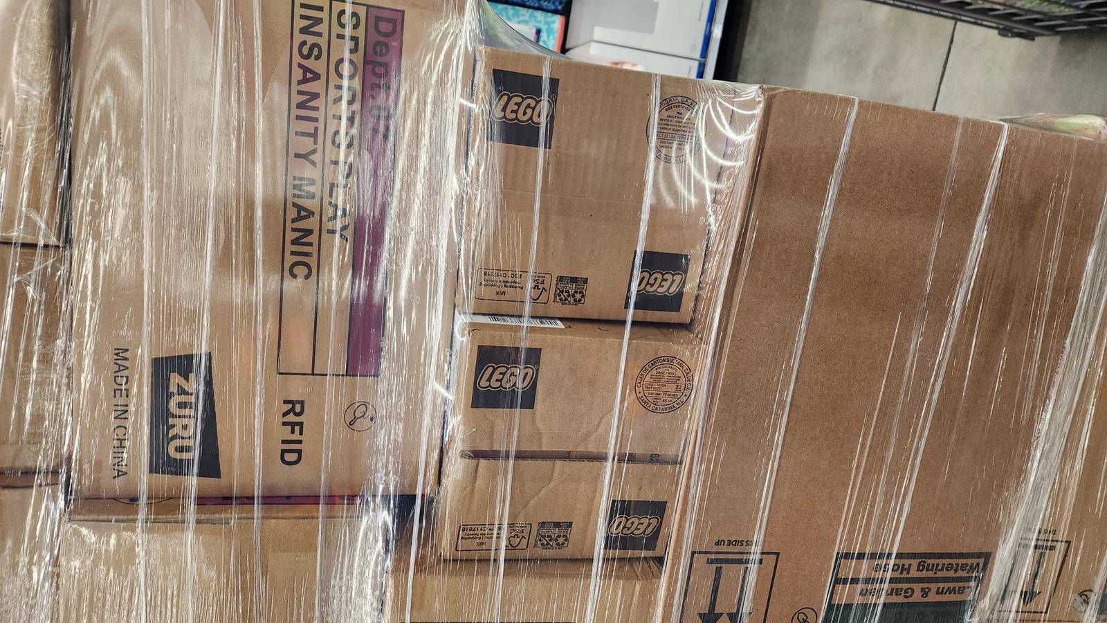 Shrink-wrapped pallet of LEGO shipping boxes at a retail store  -  new sets arriving for restocking